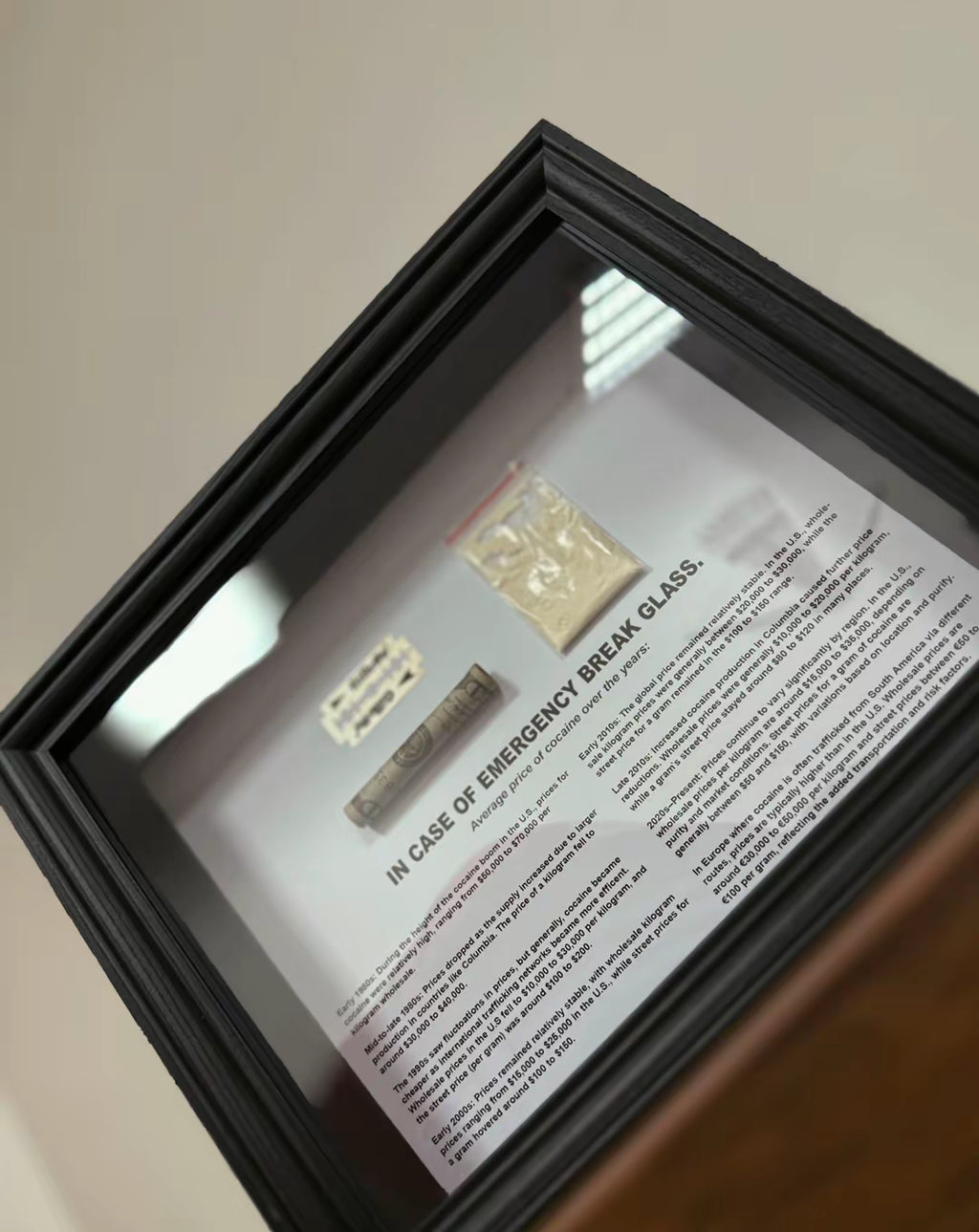 Angled view of object100™ Emergency C0C A1 NE Dollar Frame in black wooden frame