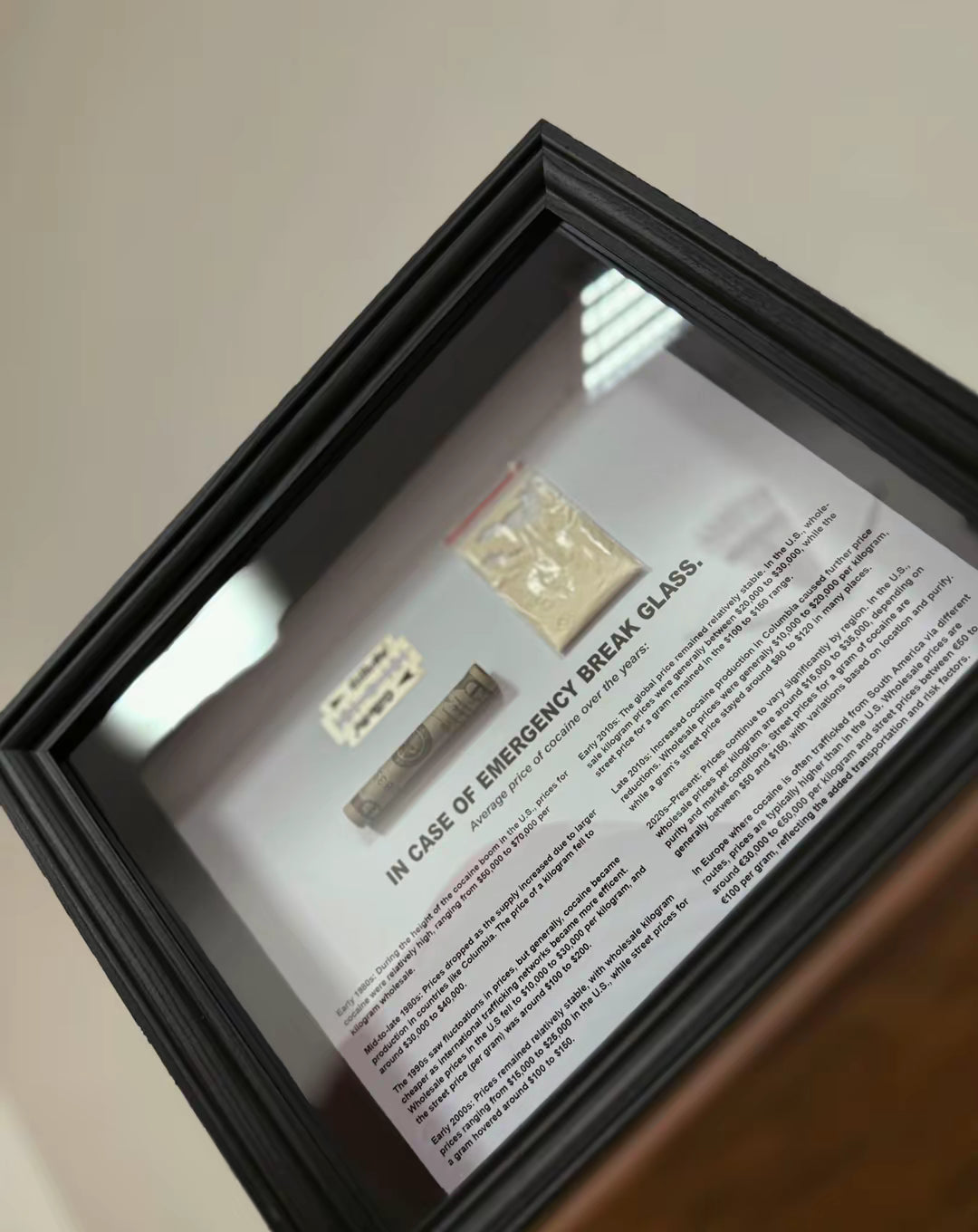 Angled view of object100™ Emergency C0C A1 NE Dollar Frame in black wooden frame